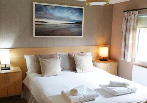 Saint MinverMariners Lodge的卧室配有白色的床和2条毛巾