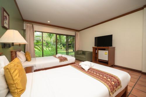 北碧Comsaed River Kwai Resort SHA的酒店客房设有两张床和电视。