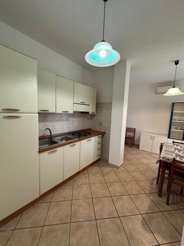 波萨达Grazioso appartamento a Posada的厨房配有白色橱柜和瓷砖地板。