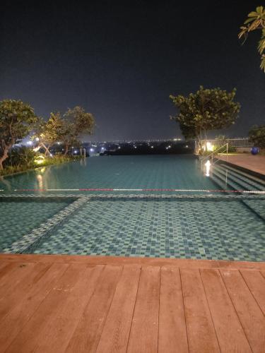 贝克西Capital O 93854 Apartemen Sayana By Sentra Jaya的一个夜晚有灯光的空游泳池