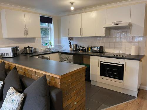 沃特福德SAV 1 Bedroom Flat near Watford Town Centre的厨房配有白色橱柜和黑色台面