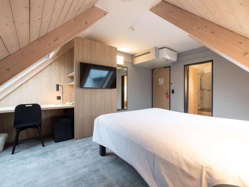 库尔库尔宜必思酒店的一间卧室设有一张大床和一台墙上的电视。