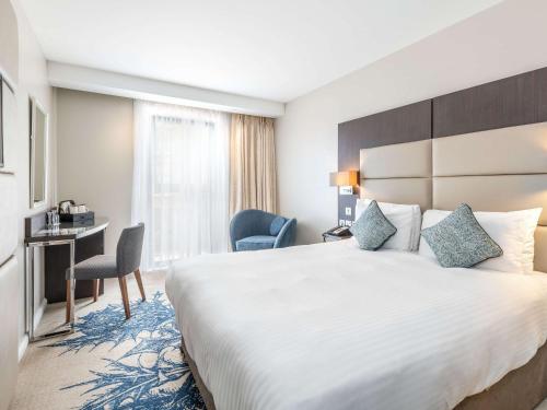 爱丁堡爱丁堡干草市场美居酒店的酒店客房设有一张大床和一张书桌。
