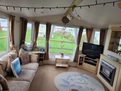LlwyngwrilCosy caravan Sunbeach的带沙发和电视的客厅