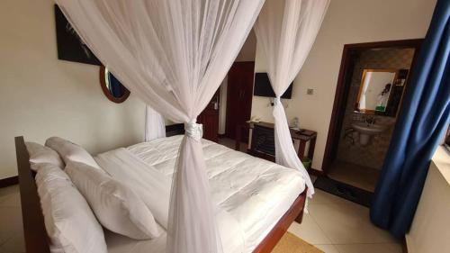 MbaleMountain Inn Hotel的卧室配有带白色窗帘和水槽的床