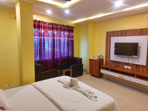 ForbesganjHotel Shobha Forbesganj的配有一张床和一台平面电视的酒店客房