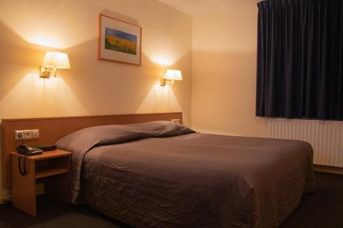 利赫滕福德Hotel Bi-j Ons的卧室配有一张床,墙上有两盏灯