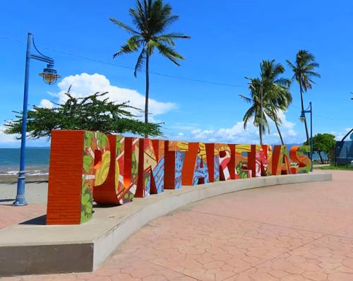 蓬塔雷纳斯Hostel del Pacífico的海滩上带有读取三联字的标志的栅栏