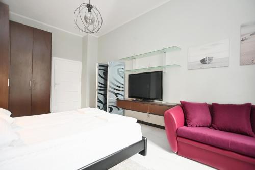 索波特Victus Apartamenty, Apartament Niebieski的一间卧室配有一张床、一张沙发和一台电视。