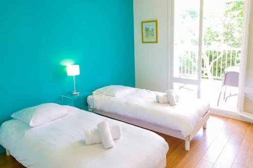 比亚里茨Splendide appartement de 75m2 avec place de parking à Biarritz tout inclus的蓝色墙壁客房的两张床