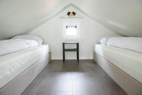 哈尔德韦克Camping de Konijnenberg Tiny House的阁楼设有2张白色的床和窗户