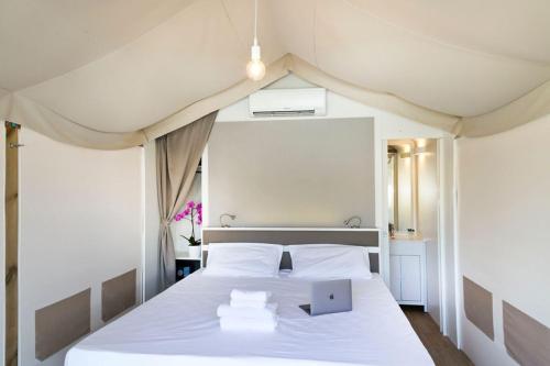 马格拉hu Venezia Camping in Town的一间卧室配有一张白色的床,上面有笔记本电脑
