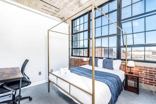 圣路易斯STUNNING Architect loft by CozySuites的卧室配有一张床、一张书桌和窗户。