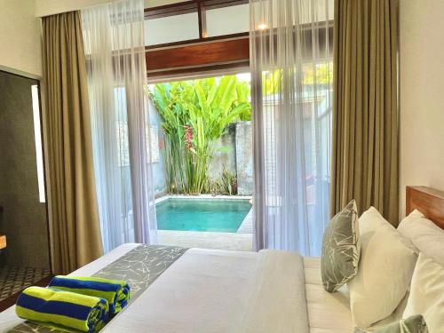 登巴萨Livin Sanur Villa的一间卧室配有一张床,享有游泳池的景色