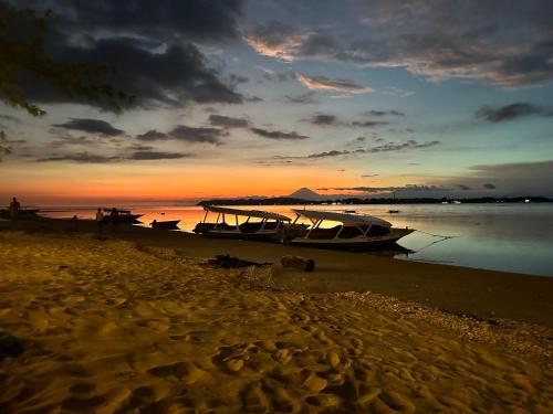 吉利阿尔Sunny Rose Bungalows Gili Air的日落时坐在海滩上的船只