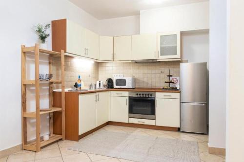 布达佩斯Budapest Opera Apartment的厨房配有白色橱柜和不锈钢冰箱