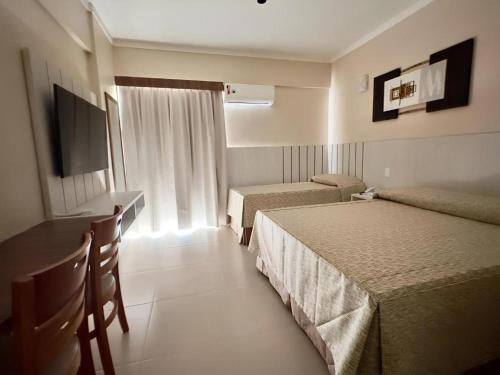 卡达斯诺瓦斯Spazzio Diroma Com acesso gratuito ao Acqua Park - R的酒店客房设有两张床、一张桌子和一台电视。