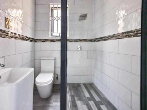 卢萨卡Kumwitu Luxury Apartments的白色的浴室设有卫生间和水槽。