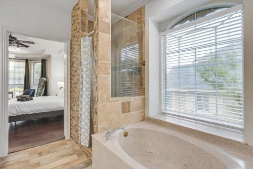 普莱诺Creekside Charm w Pool Backyard Oasis Patio的带浴缸的浴室和大窗户