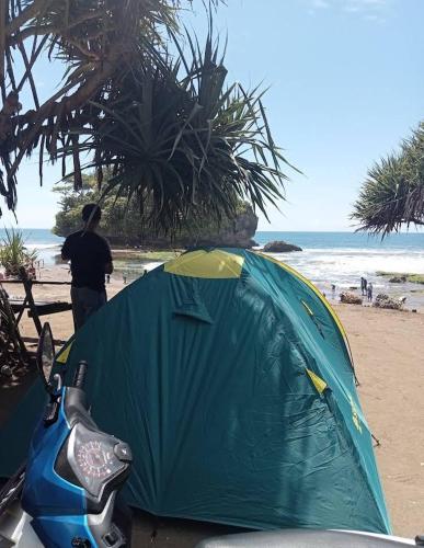 BulakbendaMadasari Outdoor Camping Tenda Paket Hemat的站在海滩帐篷旁的人