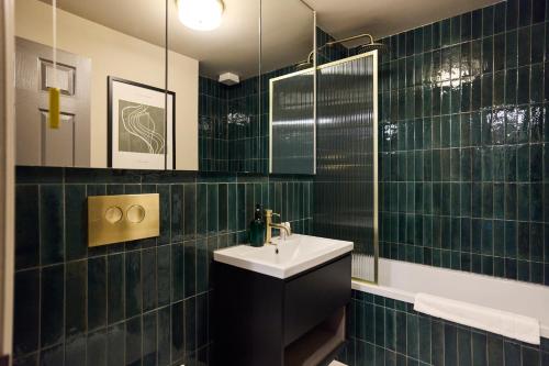 特威克纳姆The Twickenham Wonder - Lovely 1BDR Flat with Parking的绿色瓷砖浴室设有水槽和镜子