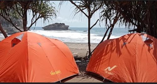 BulakbendaMadasari Outdoor Camping Tenda Paket Komplit的海边两顶橙色帐篷