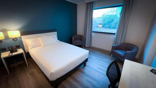 圣地亚哥Hotel Diego de Almagro Pudahuel Aeropuerto的卧室配有床、椅子和窗户。