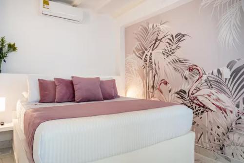 圣玛尔塔卡萨福尔德酒店的一间卧室配有一张带紫色枕头的床和壁画