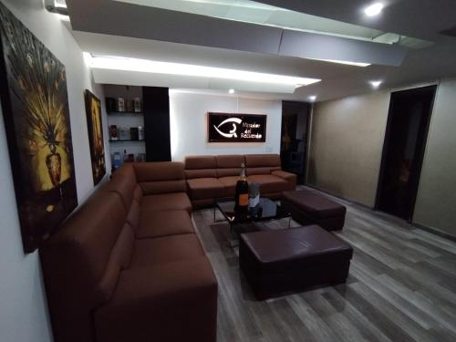 波哥大Aparta-Suites Mirador del Recuerdo的客厅配有棕色沙发和桌子