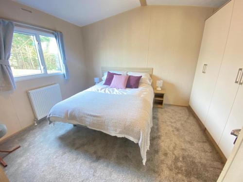 莫克姆Angella's Caravan - Morecambe的卧室配有带粉红色枕头的大型白色床