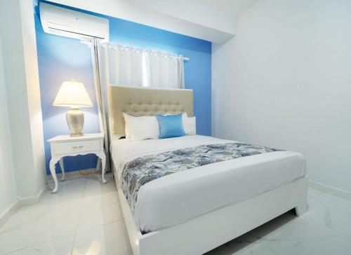 Las FloresCharming 2 bed 1 bath with Pool的卧室配有白色的床和蓝色的墙壁