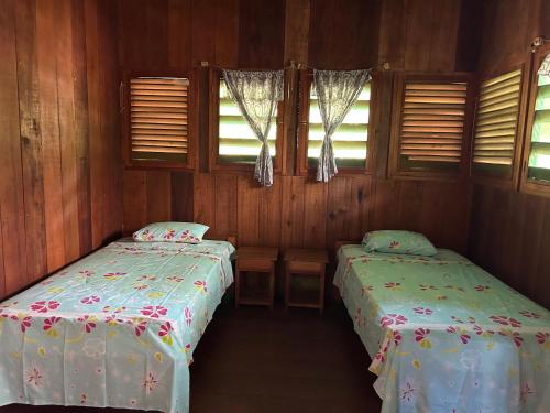 利马Chamisal Jungle Hotel的配有木墙和窗户的客房内的两张床