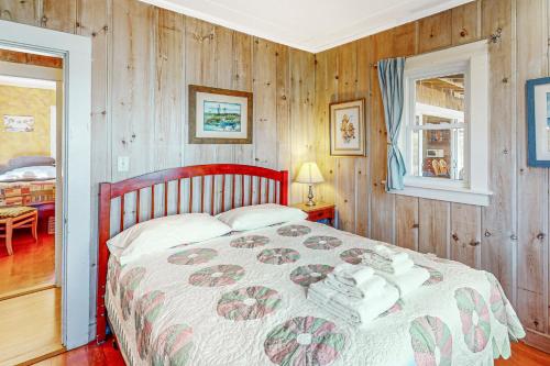 East FalmouthCove Cottage的卧室配有一张床铺,位于带木墙的房间内