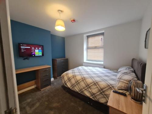 EstonCozy 6 Bedroom HMO的卧室配有一张床,墙上配有电视。