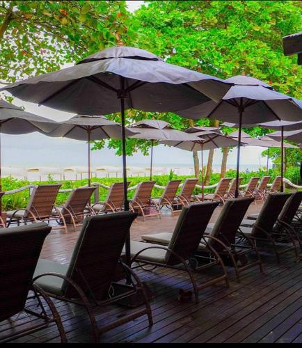 塞古罗港Resort All Inclusive Arcobaleno的甲板上的一大堆椅子和遮阳伞