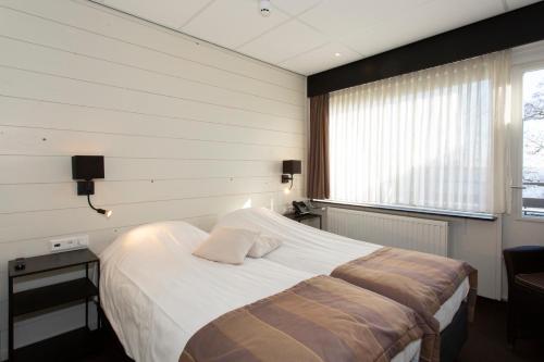 Noorden沃特格斯餐厅酒店的一间卧室设有一张大床和一个窗户。