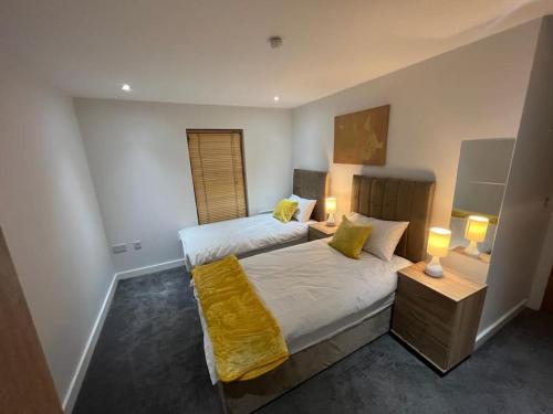 曼彻斯特AO Arena flat Manchester, with parking的一间卧室配有两张带黄床单和两盏灯的床。