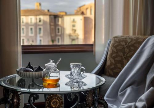 罗马Anantara Palazzo Naiadi Rome Hotel - A Leading Hotel of the World的一杯酒和一碗食物的玻璃桌