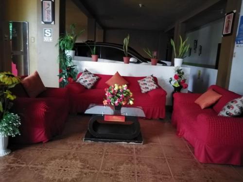 普卡尔帕Hospedaje Kennedy的客厅配有红色的沙发和带鲜花的桌子