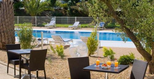 布格奈斯停泊港南特大洋洲酒店的游泳池旁的两张桌子和椅子