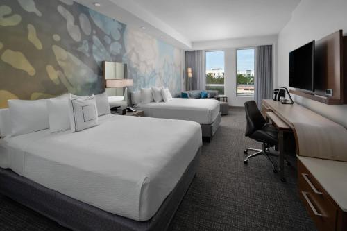 德尔雷比奇Courtyard by Marriott Delray Beach的酒店客房配有两张床和一张书桌