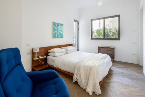 特拉维夫Heart of Tel Aviv Garden Oasis by Sea N' Rent的一间卧室配有一张床和一张蓝色椅子