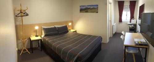 库马库马汽车旅馆的一间卧室配有床、两张桌子和一台电视