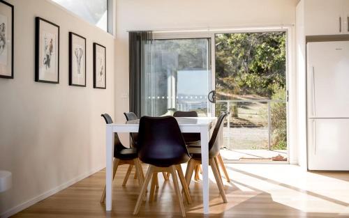 AlonnahCouples Getaway on Bruny Island的一间配备有白色桌子和黑色椅子的用餐室