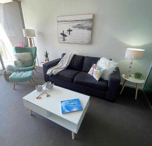 纽卡斯尔AQUA 306 POOLSIDE Luxury Apartment , Honeysuckle, NEWCASTLE FREE Parking的客厅配有蓝色的沙发和茶几