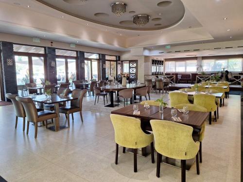 布达佩斯多瑙花园酒店的餐厅设有木桌、椅子和窗户。