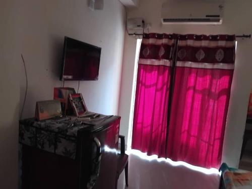 马图拉Apartment in Omaxe, Vrindavan的一间设有红色窗帘和窗户的房间
