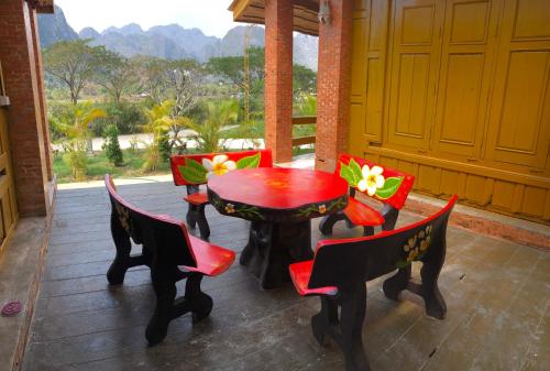 万荣Vang Vieng Romantic Resort的美景庭院里配有红色的桌椅