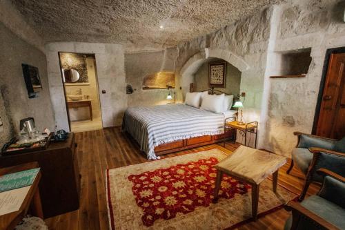 格雷梅Aza Cave Cappadocia Adult Hotel的石墙客房的卧室配有一张床