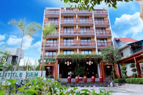 会安Little Gem. An Eco-Friendly Boutique Hotel & Spa的一座高大的粉红色建筑,前面有树木